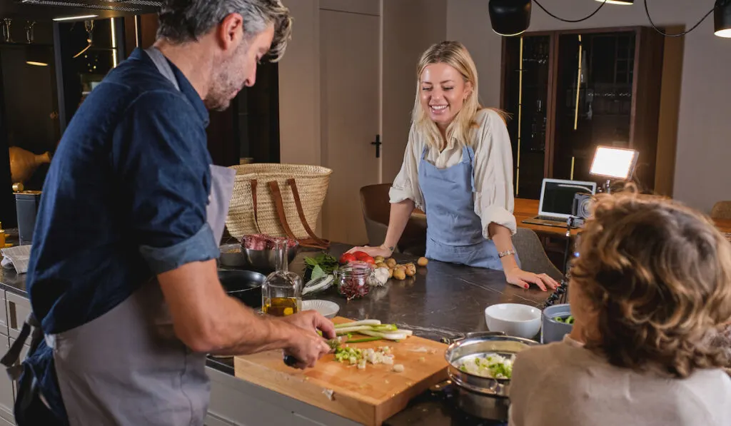 man preparing dinner, cooking dinner with his family in modern kitchen at home