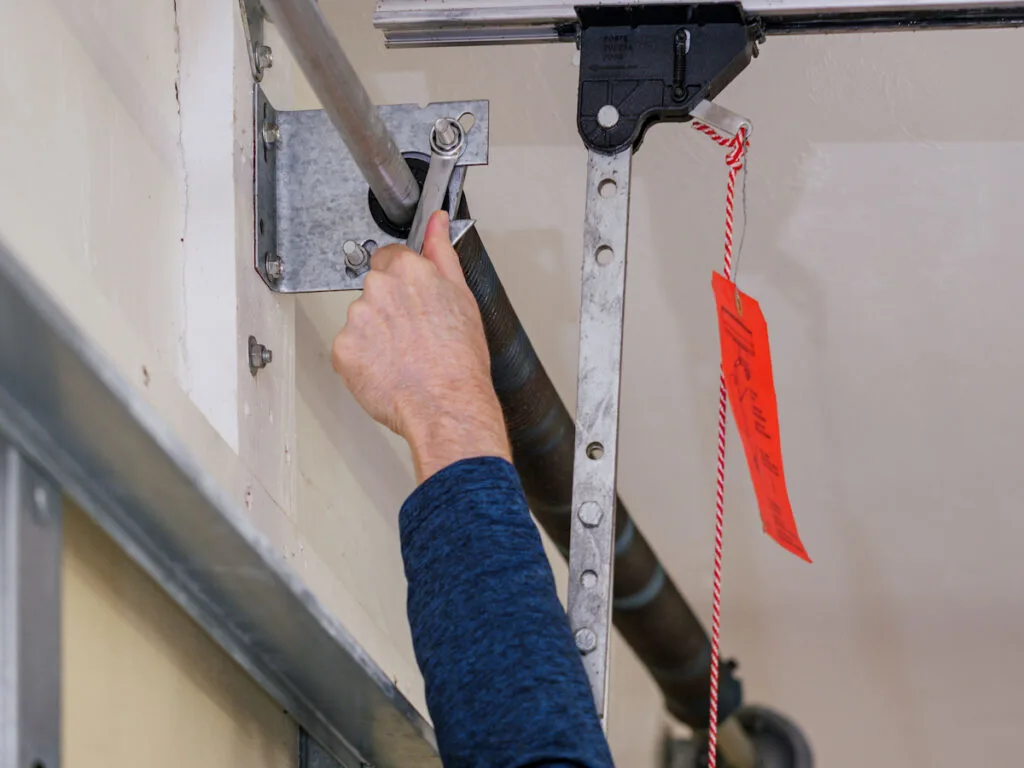 Man repairing electric garage door coiled tension spring - ss230428