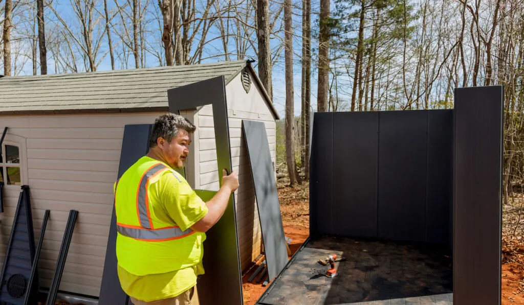 Construction worker putting together shed carefully to ensure that shed is assembled correctly