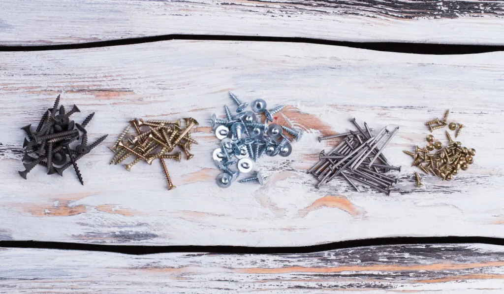 Different screws and nails on wooden background