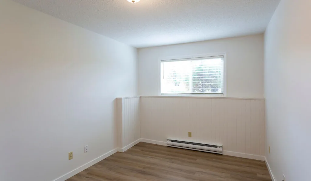 Interior of empty renovated room with Electric Baseboard Heater with white walls