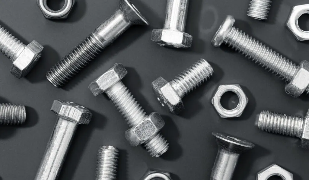 Variety of metallic nuts and bolts on black background