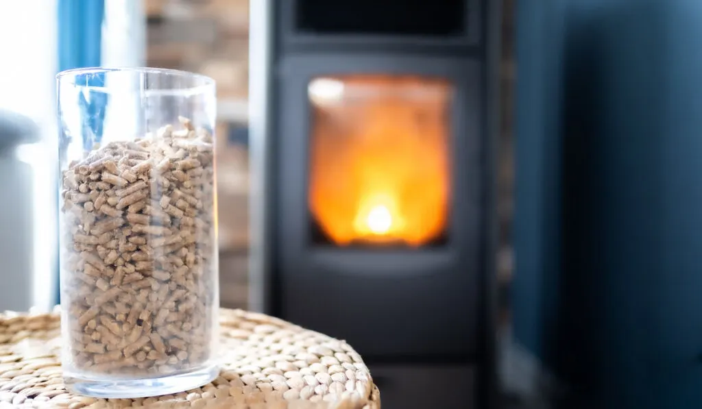 a pot of pellets in glass jar to heat the fireplace with a stove in the background