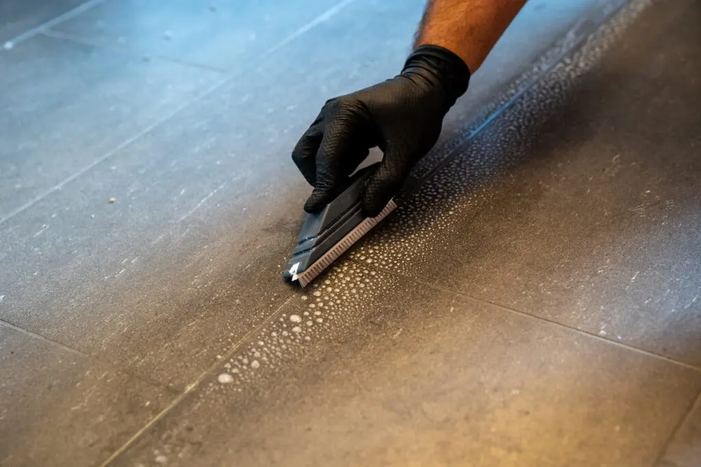 professional cleaner cleaning grout with a brush blade